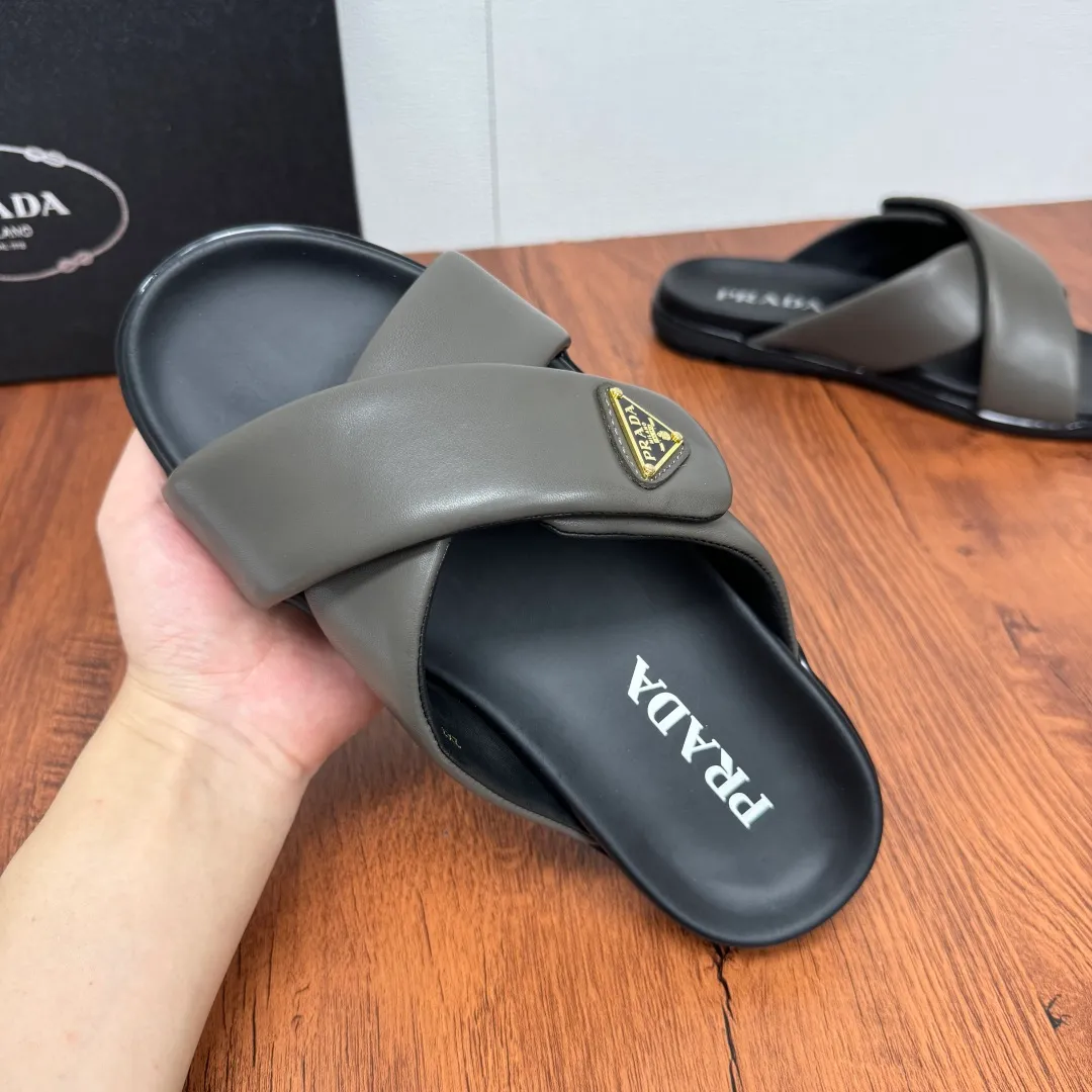 Batch 580 Prada/Prada's new men's leather cross slippers. Velcro closure can finely adjust the size. Calf leather light luxury slippers. Thick soft calf leather wraps the upper. Fat but soft rubber lazy style, soft and comfortable, excellent foot feel. Genuine leather bottom layer, cross style, with a Velcro closure buckle, easy to adjust the appropriate size, and a perfect fit for the wearing experience. The enamel gold triangle logo highlights the brand's classic features. Lightweight rubber thin sole, high foot comfort! Complete package! Size: 39-40-41-42-43-44-45 Leather shoe size Item number: 2X7132 Gray